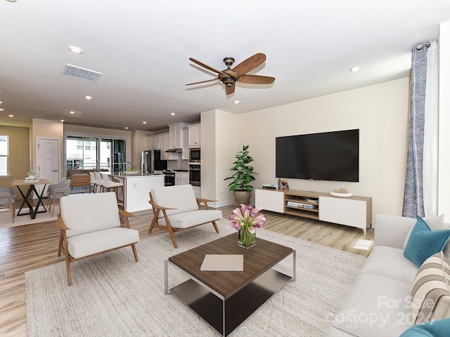 living room featuring ceiling fan and light hardwood / wood-style floors