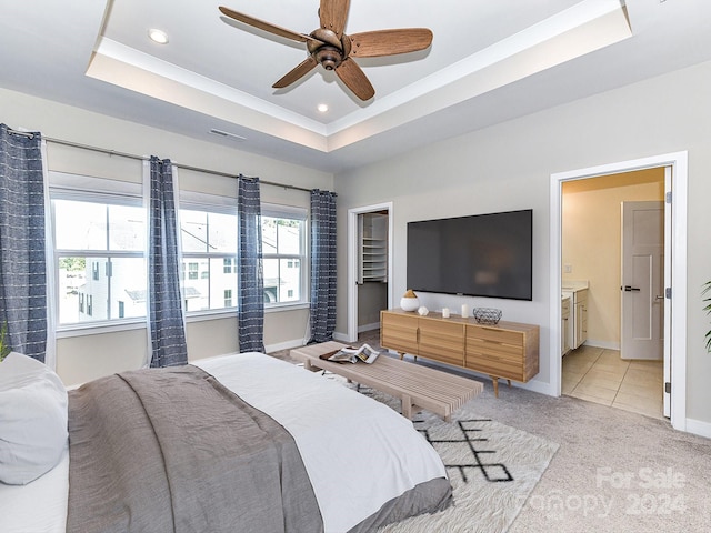 carpeted bedroom featuring ceiling fan, a raised ceiling, and ensuite bathroom