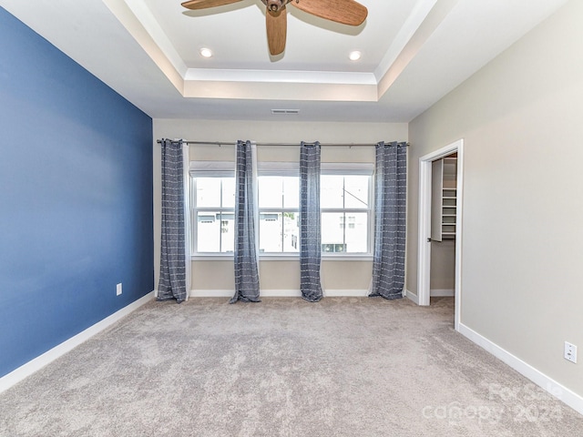 carpeted empty room with ceiling fan and a raised ceiling