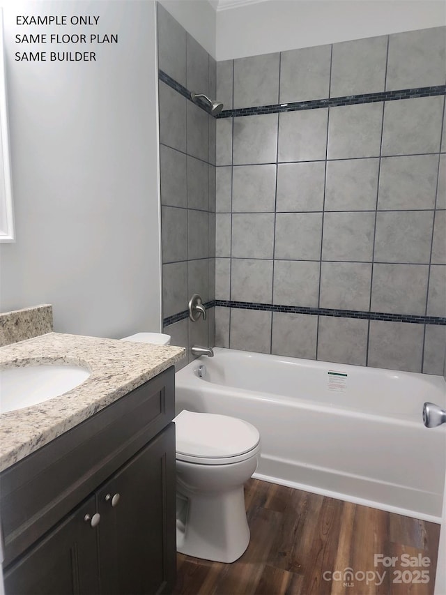 full bathroom featuring hardwood / wood-style flooring, tiled shower / bath combo, vanity, and toilet