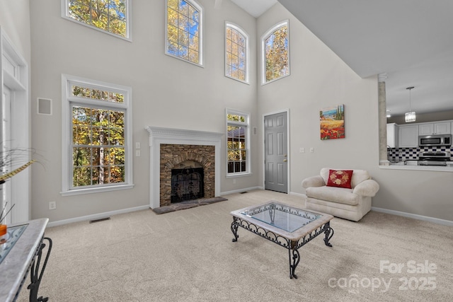 living room featuring a fireplace, light carpet, and a towering ceiling