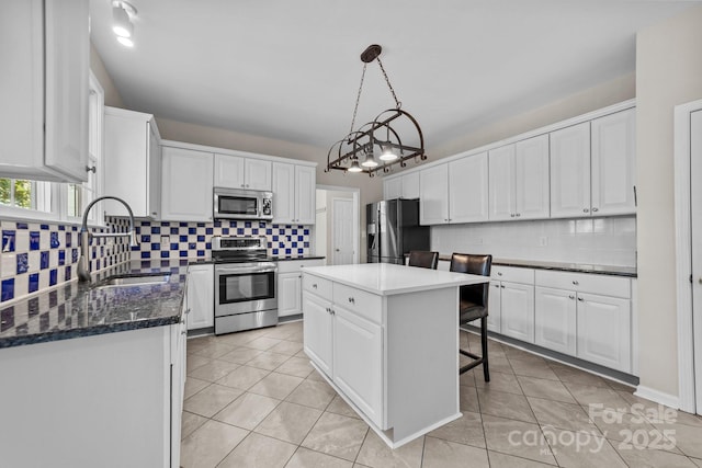 kitchen with appliances with stainless steel finishes, white cabinetry, a kitchen island, and sink