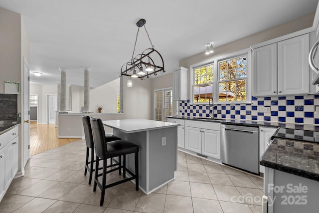 kitchen with a center island, sink, stainless steel dishwasher, decorative light fixtures, and white cabinets