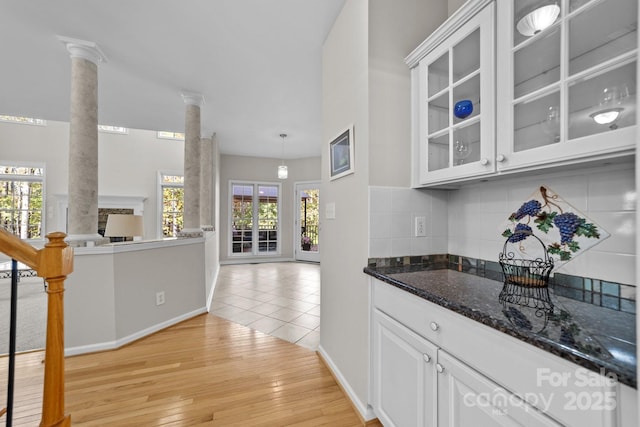 bar with white cabinetry, dark stone countertops, ornate columns, and light hardwood / wood-style flooring