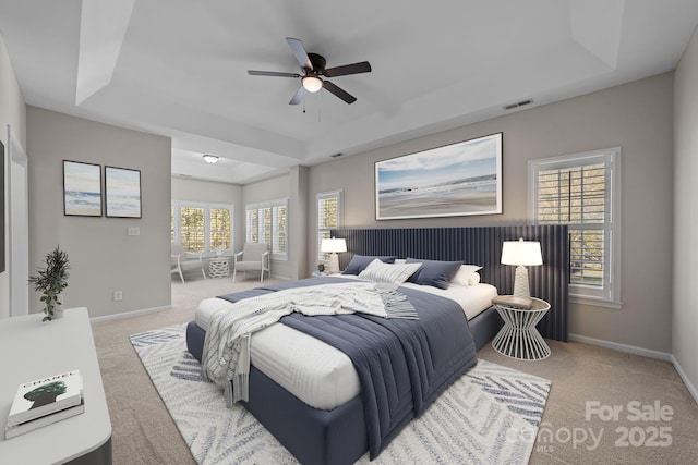 carpeted bedroom featuring a raised ceiling and ceiling fan