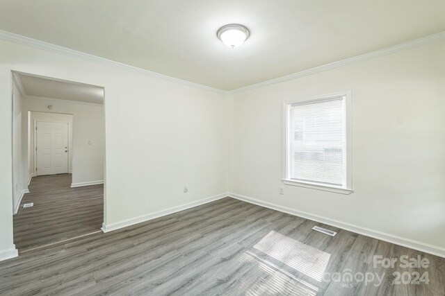 empty room with hardwood / wood-style flooring and crown molding