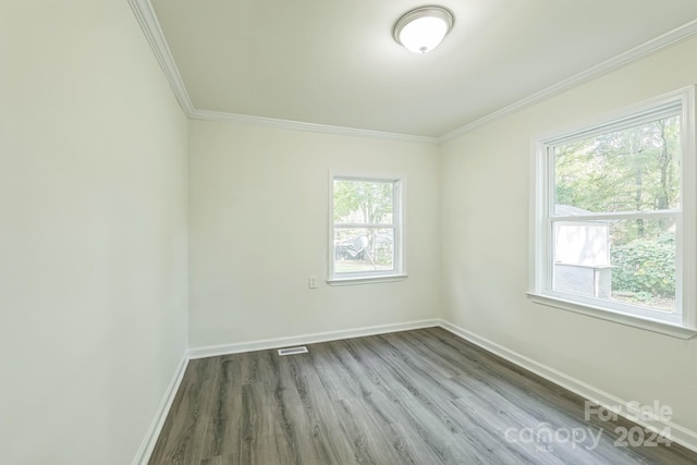 empty room with hardwood / wood-style flooring, plenty of natural light, and crown molding