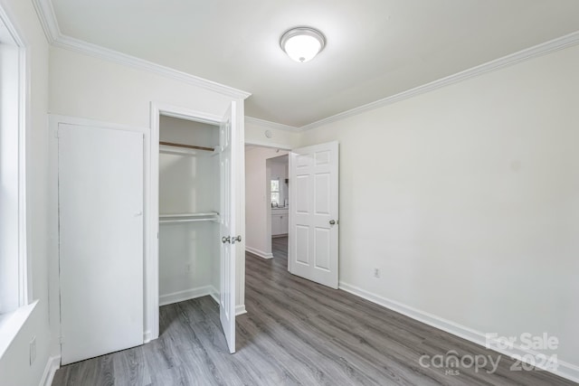 unfurnished bedroom featuring crown molding, a closet, and wood-type flooring