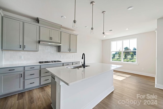 kitchen featuring gray cabinetry, hanging light fixtures, stainless steel gas stovetop, hardwood / wood-style flooring, and sink