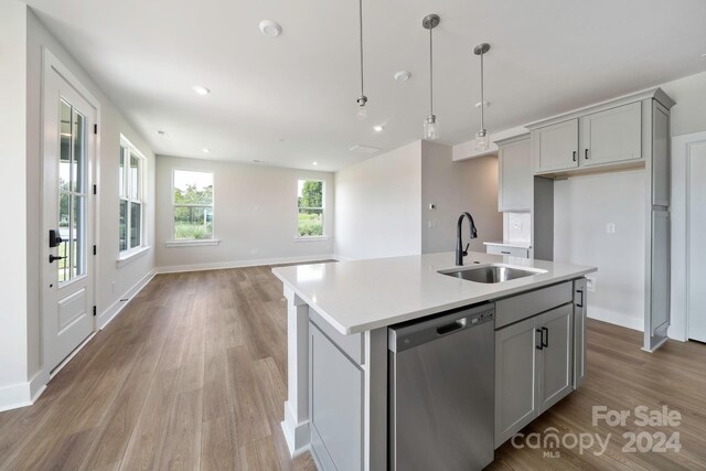 kitchen featuring light wood-type flooring, sink, gray cabinets, a kitchen island with sink, and stainless steel dishwasher