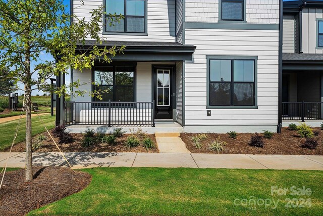 view of exterior entry featuring a porch and a lawn