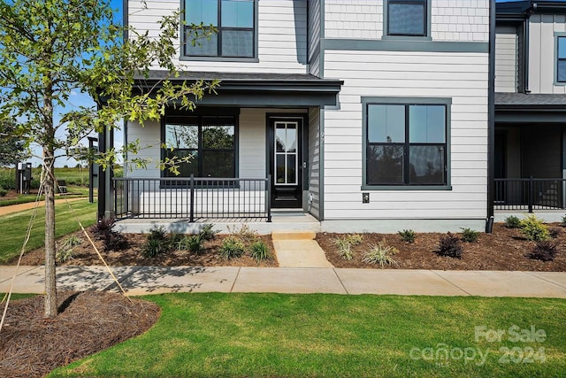 view of exterior entry with a porch and a yard