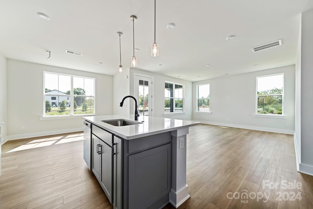 kitchen featuring visible vents, a sink, light countertops, light wood-style floors, and open floor plan