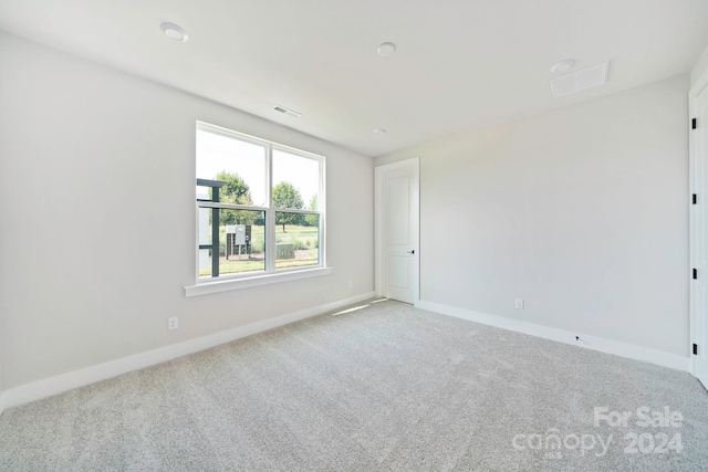 carpeted spare room with visible vents and baseboards