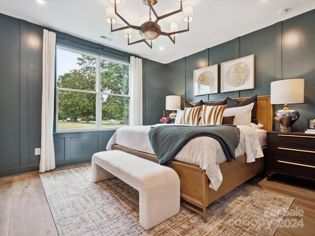 bedroom featuring multiple windows, light hardwood / wood-style flooring, and a chandelier