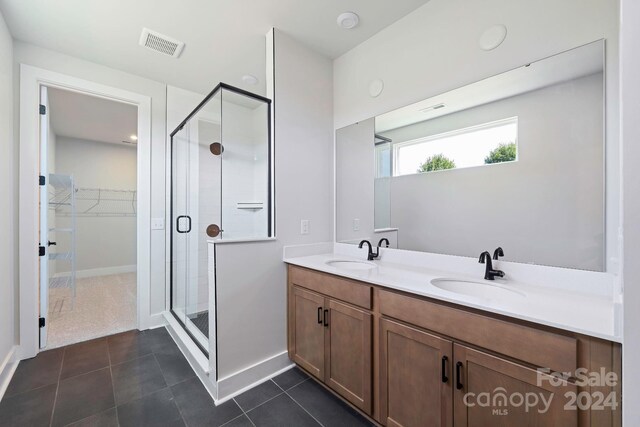 bathroom featuring tile patterned flooring, a shower with door, and vanity