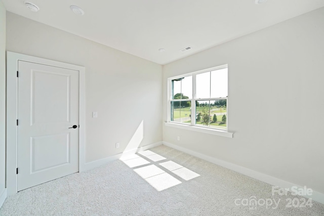 carpeted spare room featuring visible vents and baseboards