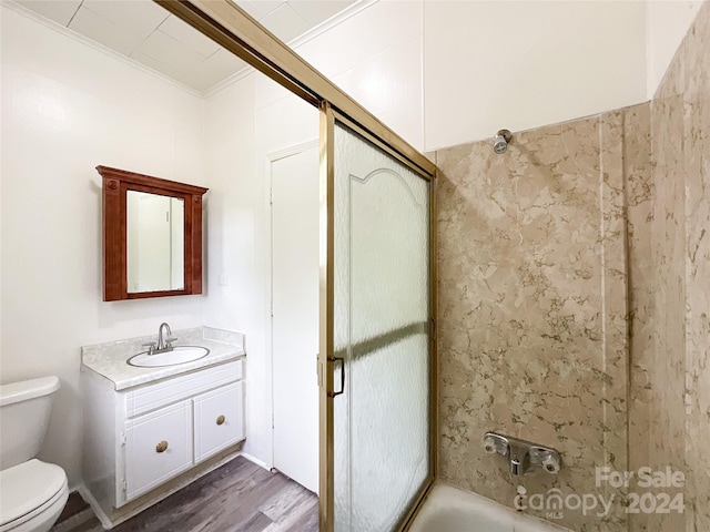 full bathroom featuring vanity, ornamental molding, wood-type flooring, combined bath / shower with glass door, and toilet