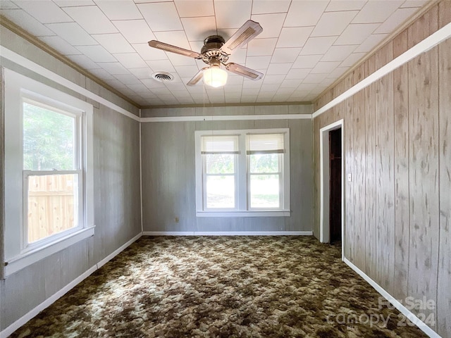 unfurnished room featuring wood walls, carpet, and ceiling fan