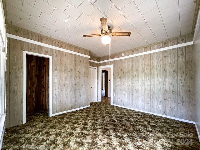 unfurnished room featuring ceiling fan and wooden walls