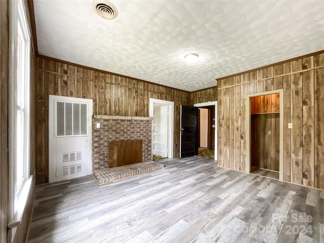 unfurnished living room featuring heating unit, a fireplace, crown molding, and light hardwood / wood-style floors