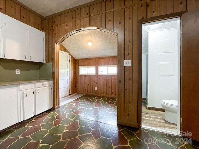 kitchen with ornamental molding, wooden walls, dark wood-type flooring, and white cabinets