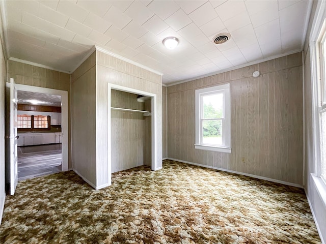 unfurnished bedroom featuring ornamental molding and wooden walls