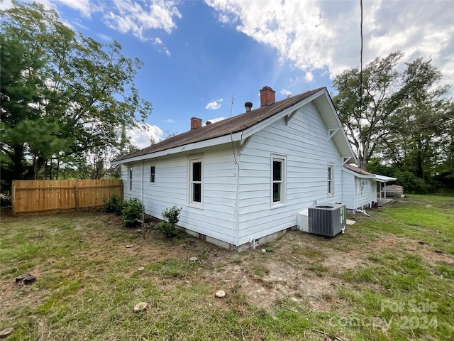 rear view of house featuring cooling unit and a lawn