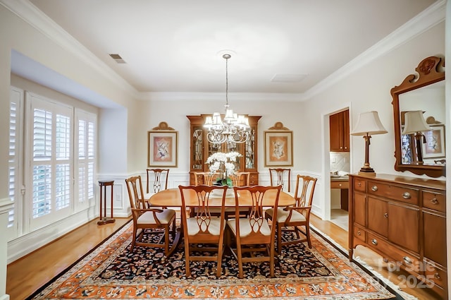 dining room featuring ornamental molding, light hardwood / wood-style floors, and a notable chandelier