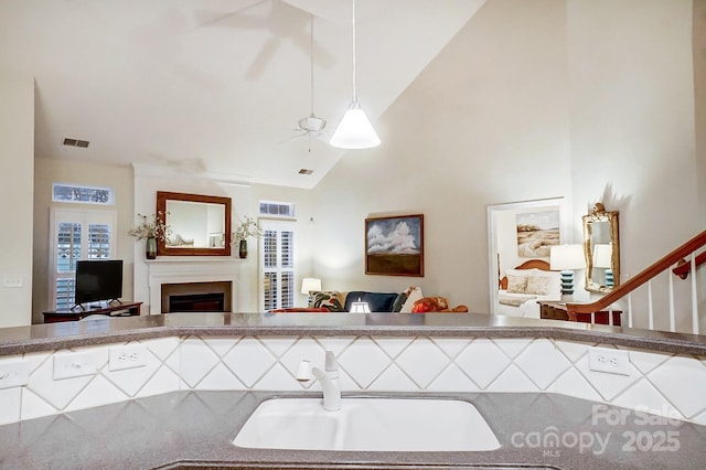 kitchen with ceiling fan, vaulted ceiling, hanging light fixtures, and sink