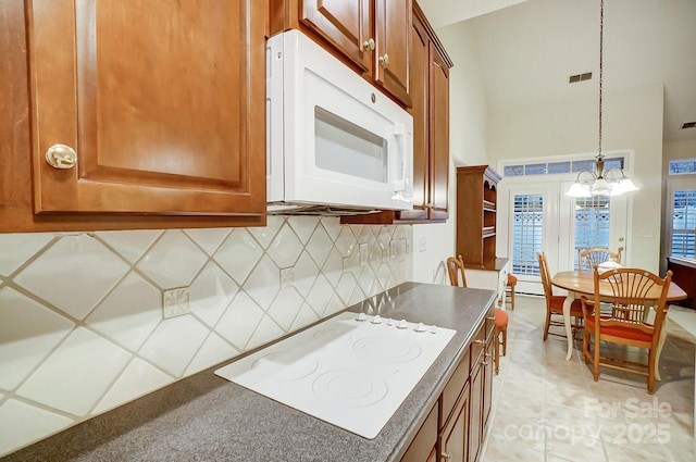 kitchen featuring an inviting chandelier, decorative light fixtures, white appliances, decorative backsplash, and light tile patterned flooring