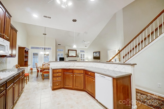 kitchen featuring sink, tasteful backsplash, white appliances, decorative light fixtures, and ceiling fan with notable chandelier