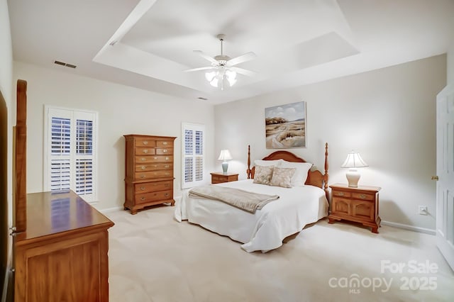 carpeted bedroom featuring ceiling fan and a tray ceiling