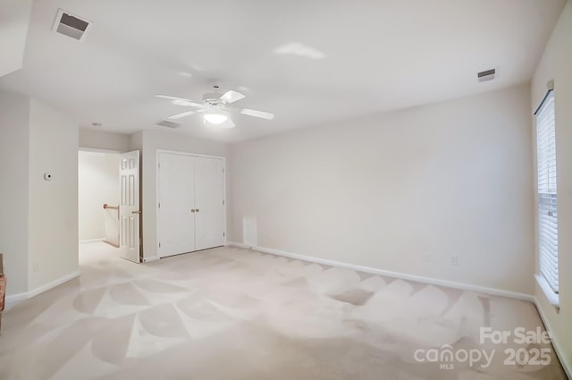 unfurnished bedroom featuring ceiling fan, a closet, and light carpet