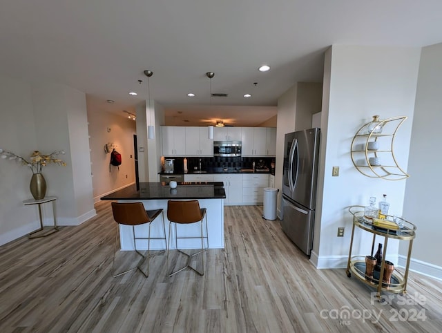 kitchen with appliances with stainless steel finishes, light hardwood / wood-style floors, a center island, decorative backsplash, and white cabinetry