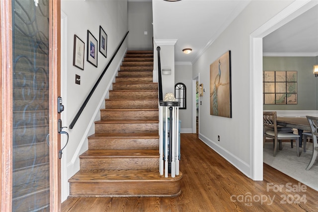 staircase featuring wood-type flooring and crown molding