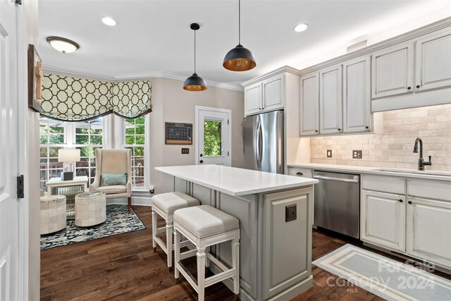 kitchen with pendant lighting, sink, dark wood-type flooring, appliances with stainless steel finishes, and a center island