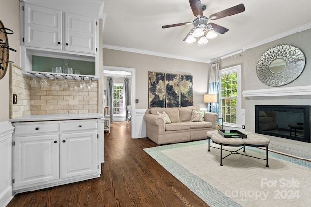 living room with crown molding, a fireplace, dark wood-type flooring, and ceiling fan