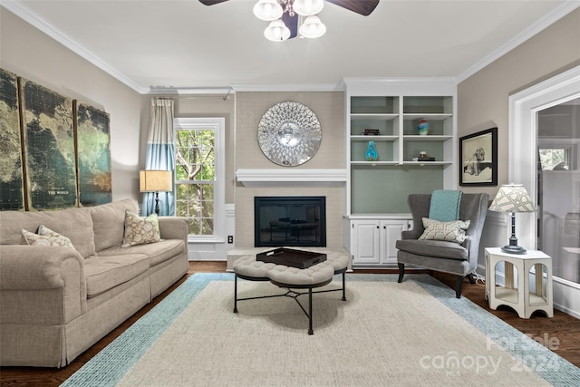 living room featuring ceiling fan, ornamental molding, a brick fireplace, and hardwood / wood-style floors