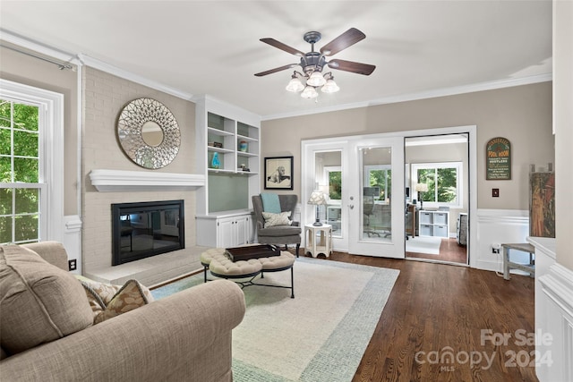 living room featuring a healthy amount of sunlight, a fireplace, wood-type flooring, and ceiling fan