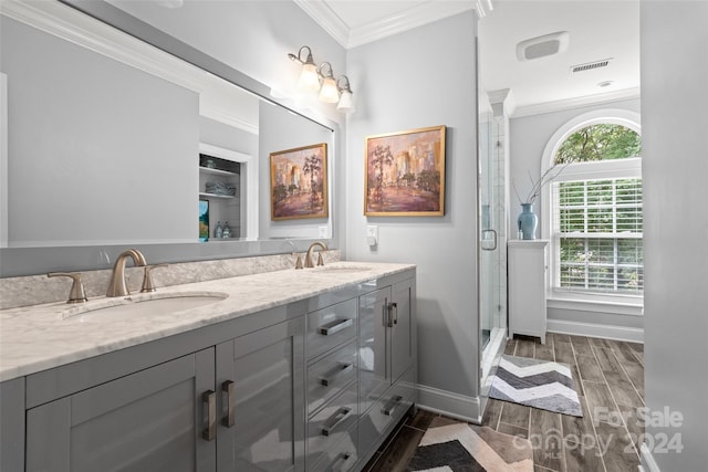 bathroom featuring hardwood / wood-style flooring, ornamental molding, vanity, and a shower with shower door