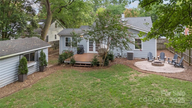 rear view of property with a wooden deck, an outbuilding, cooling unit, a fire pit, and a lawn