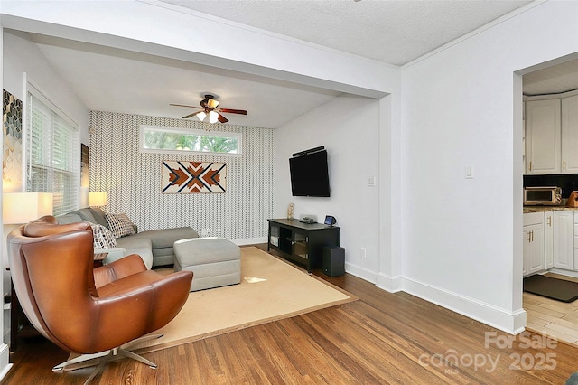 living room featuring hardwood / wood-style flooring, ceiling fan, and a textured ceiling