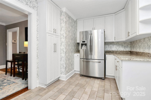 kitchen with white cabinets, light stone countertops, ornamental molding, and stainless steel refrigerator with ice dispenser