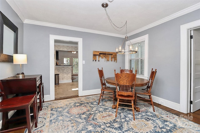 dining space featuring wood-type flooring, ornamental molding, and an inviting chandelier