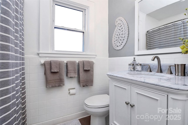 bathroom featuring vanity, toilet, and tile walls