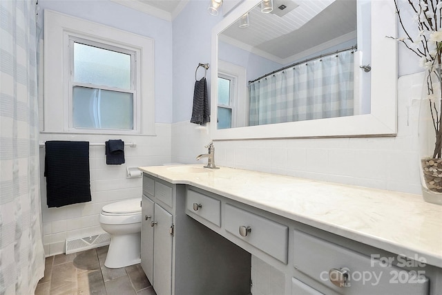 bathroom with vanity, toilet, crown molding, and tile walls