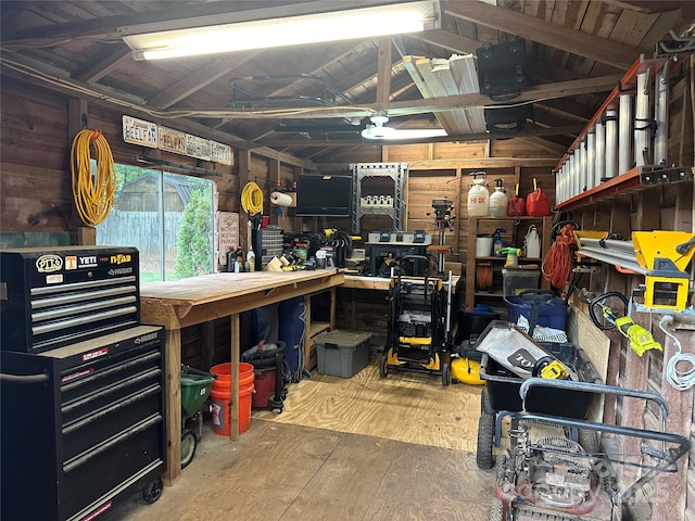 misc room with a workshop area, wooden walls, and vaulted ceiling