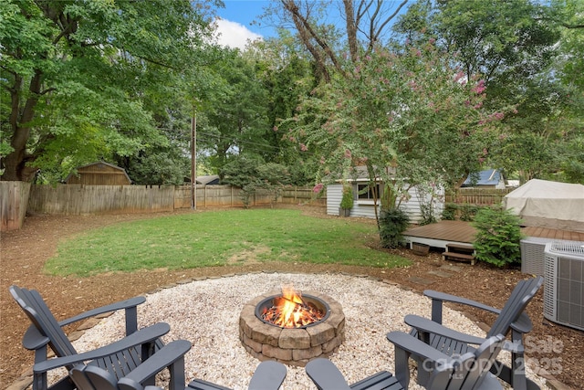 view of yard with an outdoor structure, a wooden deck, central air condition unit, and a fire pit