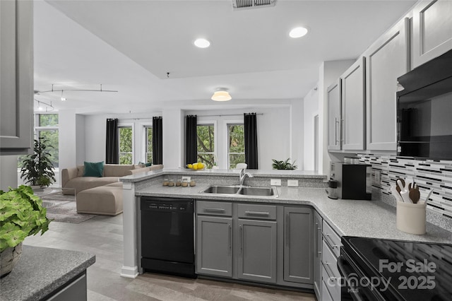 kitchen featuring kitchen peninsula, black appliances, tasteful backsplash, gray cabinetry, and sink